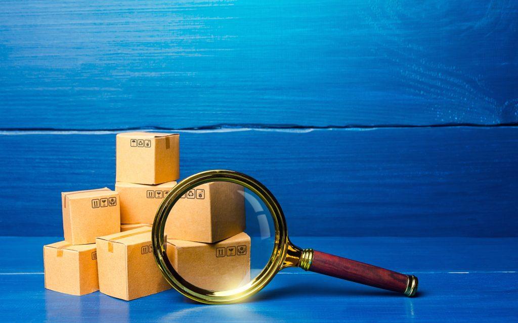 Cardboard boxes and magnifying glass. Concept of searching for goods and components
